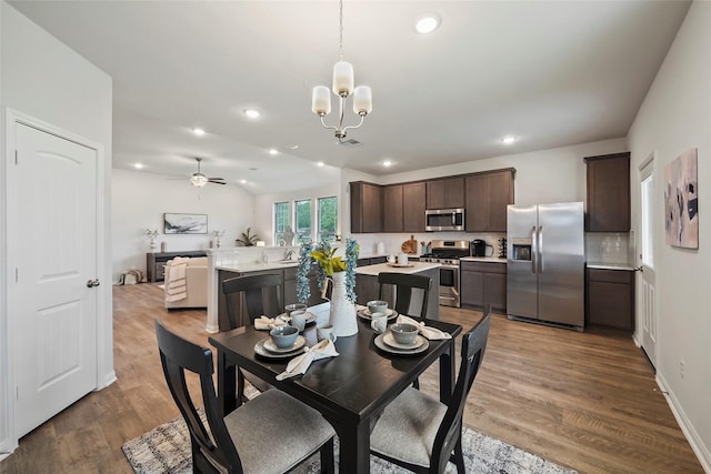 dining space featuring sink, hardwood / wood-style flooring, and ceiling fan with notable chandelier