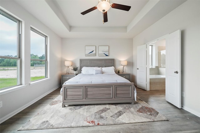 bedroom with ceiling fan, dark wood-type flooring, multiple windows, and a raised ceiling