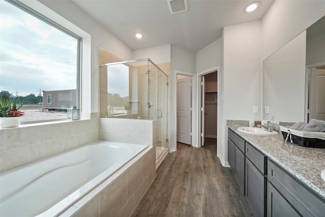 bathroom with hardwood / wood-style floors, vanity, and plus walk in shower