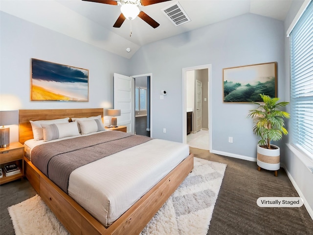 bedroom with ceiling fan, dark colored carpet, ensuite bath, and vaulted ceiling