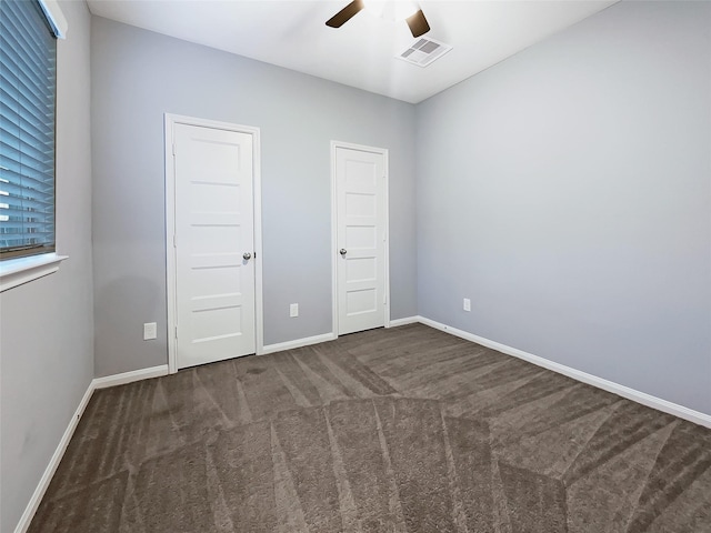 unfurnished bedroom featuring ceiling fan and dark carpet