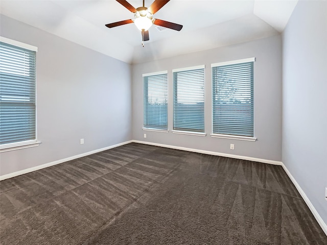 empty room featuring ceiling fan, dark carpet, and lofted ceiling