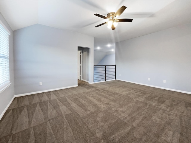 spare room with vaulted ceiling, dark carpet, and ceiling fan