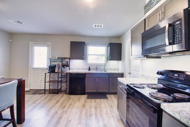 kitchen featuring light hardwood / wood-style floors, sink, dark brown cabinetry, and black appliances