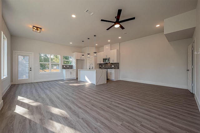 unfurnished living room with light wood-type flooring, ceiling fan, and sink