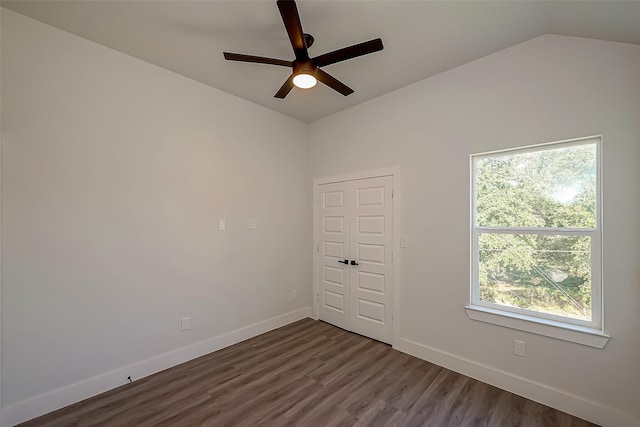 spare room featuring a healthy amount of sunlight, dark hardwood / wood-style floors, vaulted ceiling, and ceiling fan