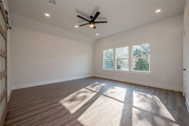 unfurnished room featuring ceiling fan, dark hardwood / wood-style flooring, lofted ceiling, and a barn door