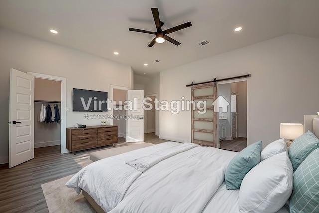 bedroom featuring a spacious closet, a barn door, a closet, ceiling fan, and connected bathroom