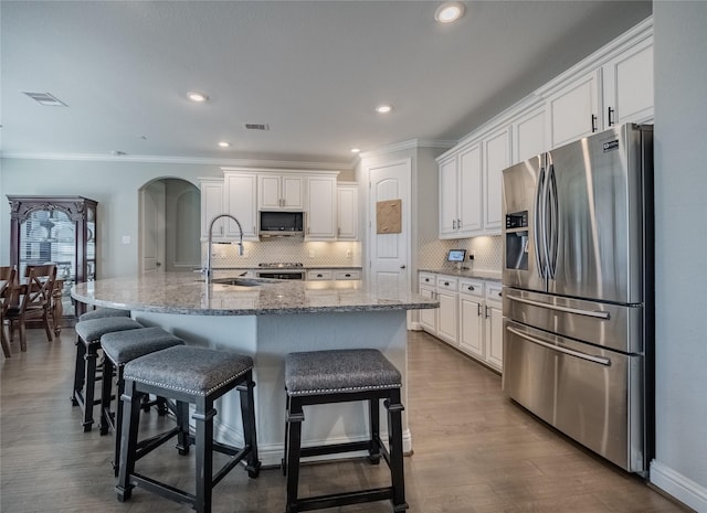 kitchen with stainless steel appliances, an island with sink, sink, and white cabinets