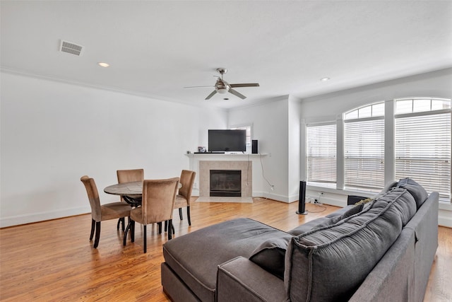 living room with a fireplace, ornamental molding, and light hardwood / wood-style floors