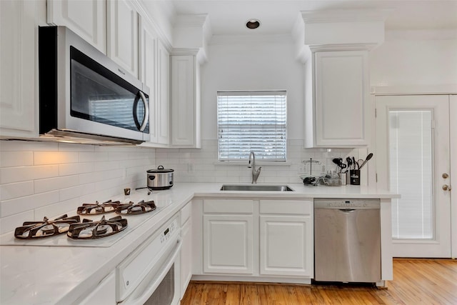 kitchen with sink, stainless steel appliances, white cabinetry, and backsplash