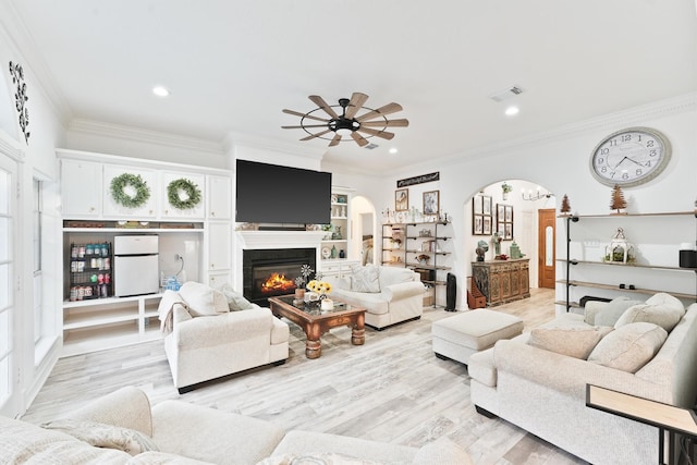 living room featuring light wood-type flooring, ceiling fan, and ornamental molding