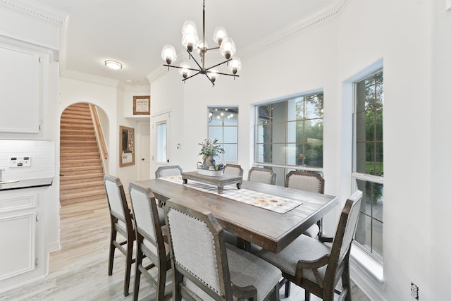 dining space with light wood-type flooring, an inviting chandelier, and ornamental molding