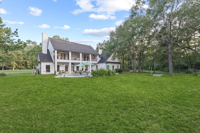 back of house featuring a balcony, a yard, and a patio area