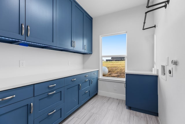 kitchen with baseboards, light countertops, and blue cabinetry