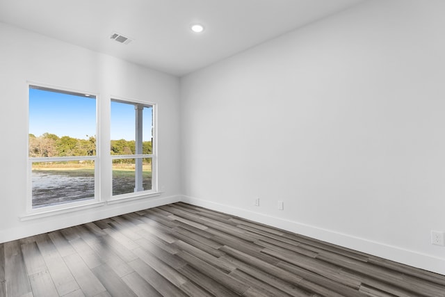 empty room featuring baseboards, visible vents, dark wood finished floors, and recessed lighting