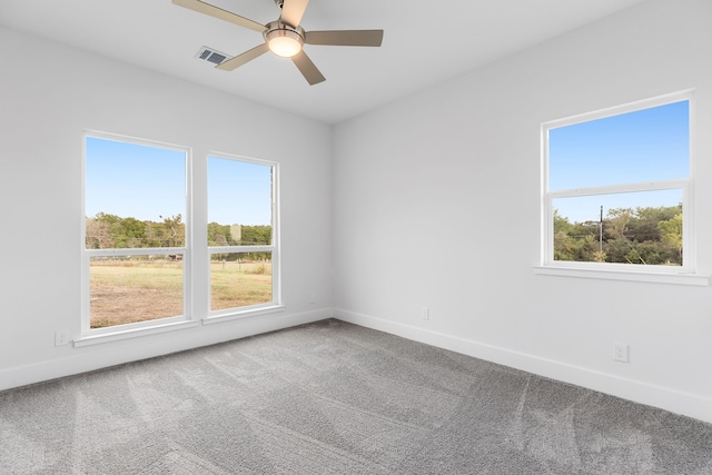 empty room featuring carpet floors, visible vents, baseboards, and a ceiling fan