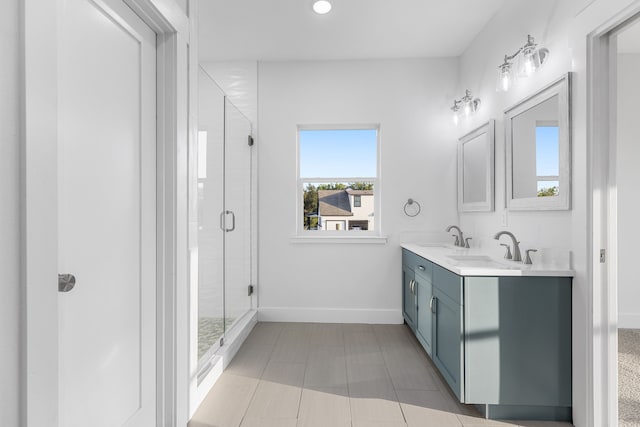 bathroom featuring double vanity, a stall shower, a sink, and baseboards