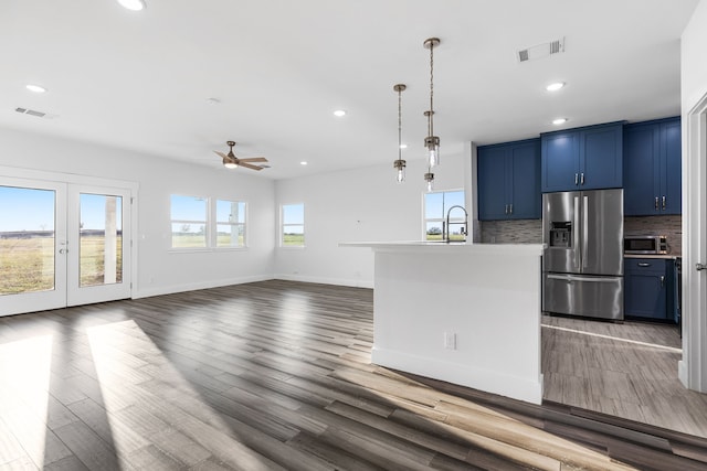 kitchen with stainless steel appliances, tasteful backsplash, light countertops, an island with sink, and blue cabinets