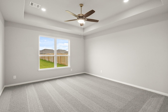 empty room featuring ceiling fan, a raised ceiling, and carpet flooring