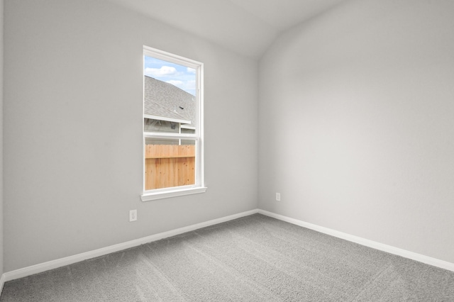 carpeted empty room with lofted ceiling