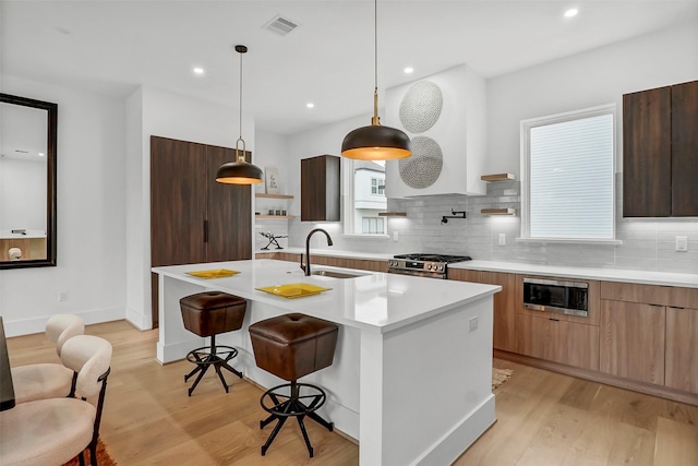 kitchen featuring sink, appliances with stainless steel finishes, plenty of natural light, pendant lighting, and a kitchen island with sink