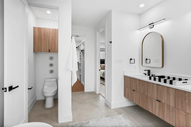 bathroom featuring vanity, concrete flooring, and toilet