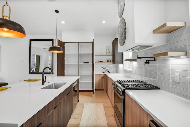 kitchen with sink, tasteful backsplash, light wood-type flooring, pendant lighting, and stainless steel appliances