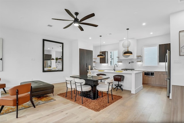 kitchen with pendant lighting, a breakfast bar area, decorative backsplash, a kitchen island with sink, and stainless steel appliances