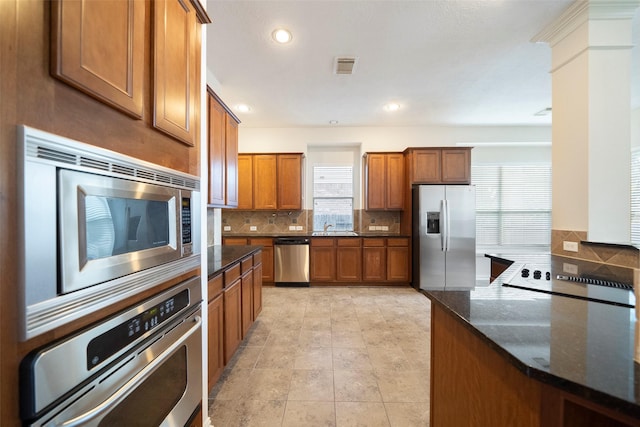 kitchen with sink, backsplash, stainless steel appliances, and dark stone countertops