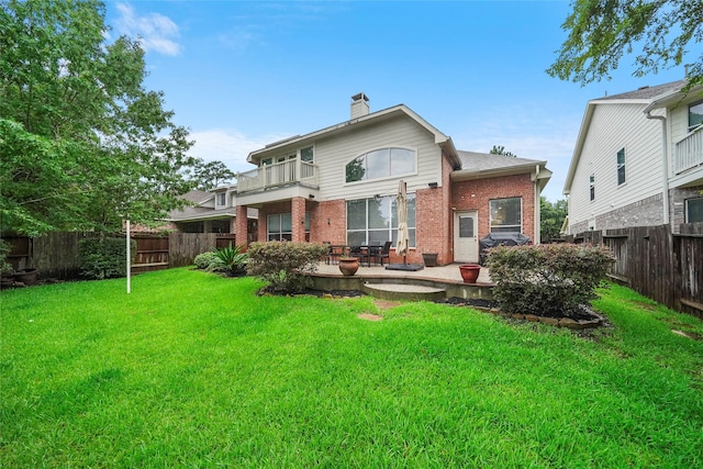 rear view of property with a balcony, a patio area, and a yard