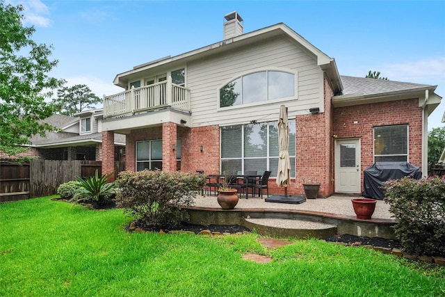 back of property featuring a balcony and a lawn