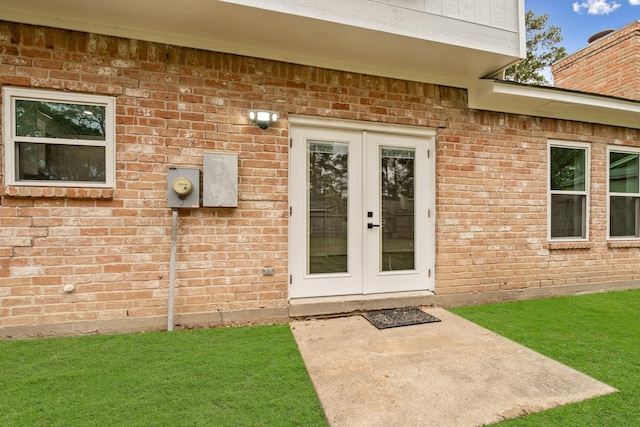 view of exterior entry featuring a patio, a yard, and french doors