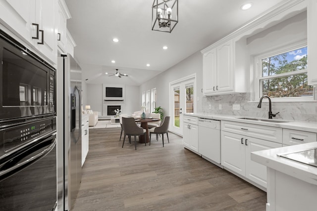 kitchen featuring wall oven, dishwasher, hanging light fixtures, white cabinets, and sink