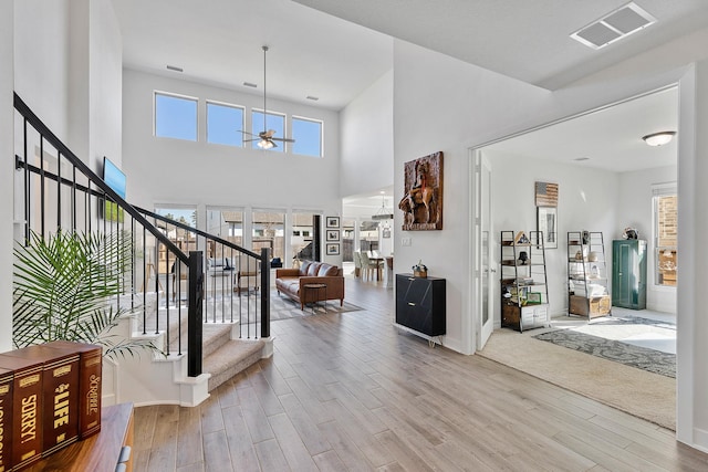 foyer entrance featuring a towering ceiling, light hardwood / wood-style flooring, and ceiling fan