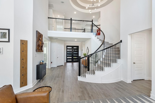 foyer entrance featuring a chandelier, light hardwood / wood-style flooring, and a high ceiling