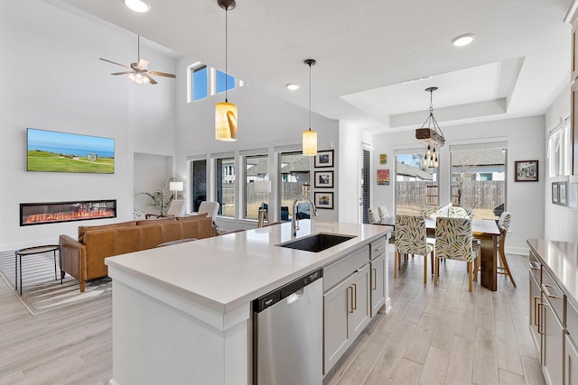 kitchen with pendant lighting, white cabinetry, dishwasher, sink, and an island with sink