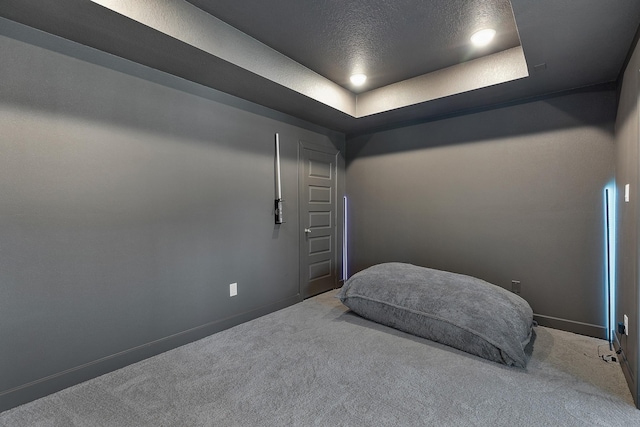 carpeted bedroom with a textured ceiling and a tray ceiling