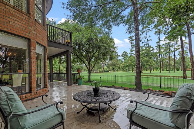 view of patio with fence and a balcony