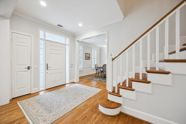 foyer entrance with light hardwood / wood-style flooring and ornamental molding