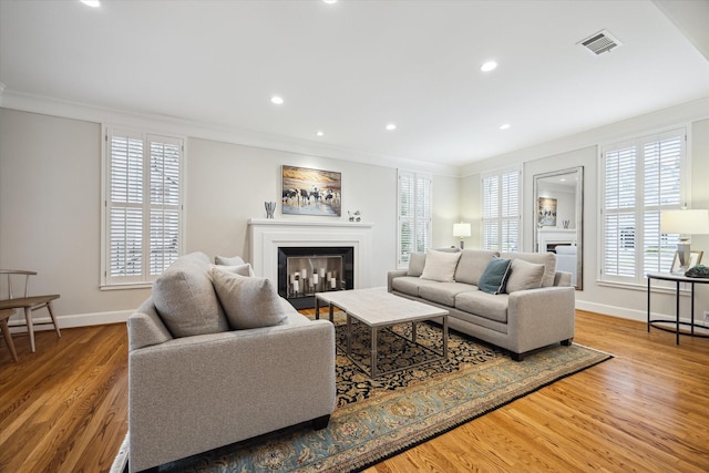 living room featuring hardwood / wood-style flooring, a wealth of natural light, and ornamental molding