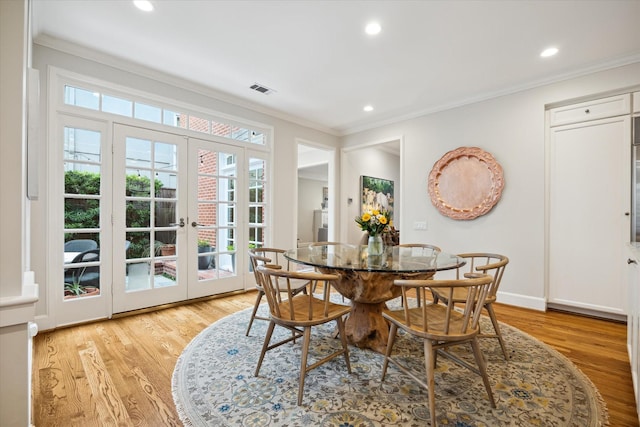 dining area featuring crown molding, light hardwood / wood-style floors, and french doors