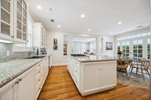 kitchen featuring light hardwood / wood-style floors, white cabinetry, sink, french doors, and light stone counters