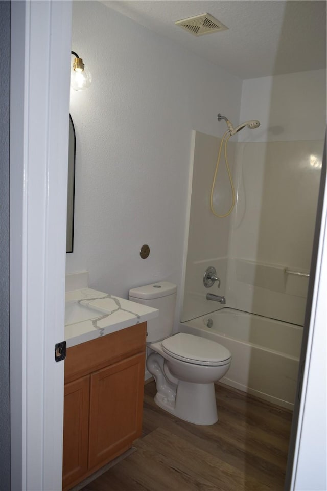 full bathroom featuring wood-type flooring, shower / bathing tub combination, vanity, and toilet