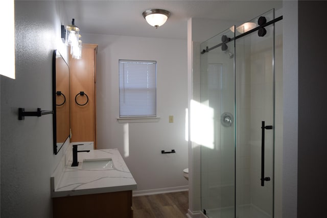 bathroom with vanity, toilet, a shower with shower door, and hardwood / wood-style floors