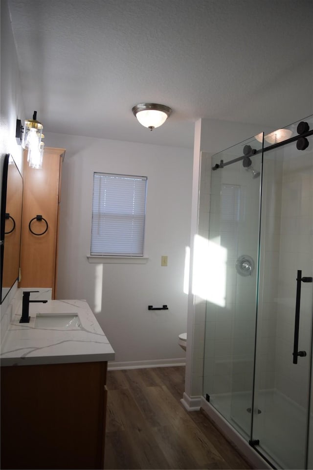 bathroom with vanity, hardwood / wood-style floors, a shower with shower door, and toilet