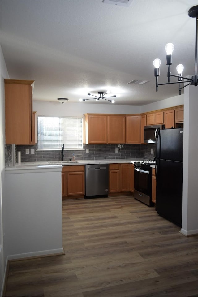 kitchen with decorative light fixtures, sink, stainless steel appliances, dark wood-type flooring, and an inviting chandelier