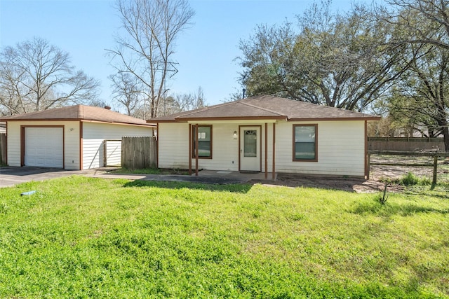 view of front of property featuring aphalt driveway, an outbuilding, a detached garage, a front yard, and fence