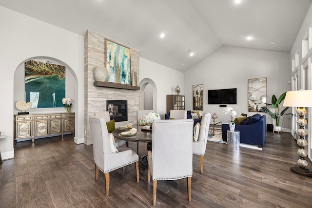 dining room with baseboards, dark wood-style flooring, a fireplace, high vaulted ceiling, and recessed lighting