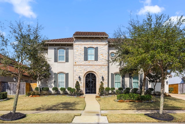 view of front of home with a tile roof, fence, a front lawn, and stucco siding